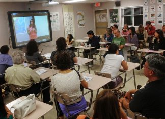 Muat Turun Video dari Internet Classroom of adults watching a video presentation on a large screen.