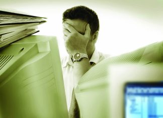 Elakkan Dokumen Hilang Ketika Bekalan Elektrik Terputus Stressed businessman overwhelmed by paperwork and computers. Preventing document loss during power outages.