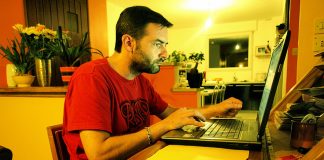 Salin Laman Web ke Komputer Man working on laptop at home desk, transferring website data to computer.