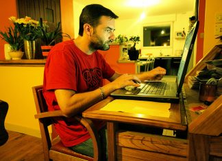 Salin Laman Web ke Komputer Man working on laptop at home desk, transferring website data to computer.