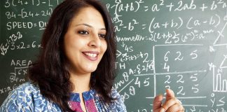 Web dan Aplikasi Mengira Soalan Matematik Smiling female math teacher explaining equations on a chalkboard.