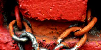 Lihat Kata Laluan Laman Web di Google Rusty padlock and chain secured to a red brick wall. The padlock is labeled "Master.