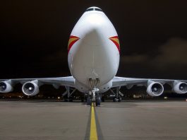 Front view of a Boeing 747 cargo plane at night on a runway.