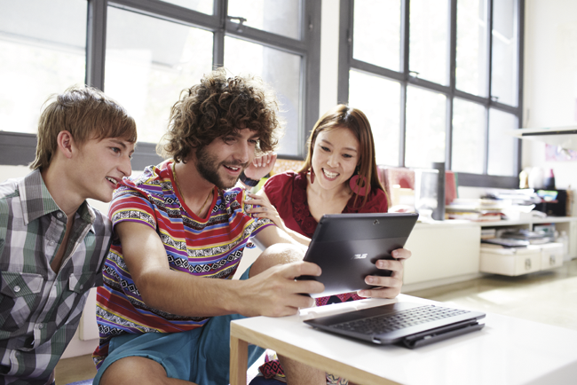 Three young adults looking at a tablet together.