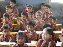 Happy schoolchildren in a classroom, clapping enthusiastically.