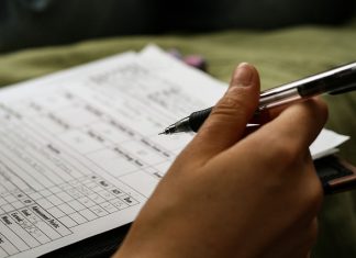 Cara Mengisi Borang dalam Format PDF di Komputer Close-up of a hand filling out a PDF form with a pen. "Advancement Points" and other relevant data are visible.