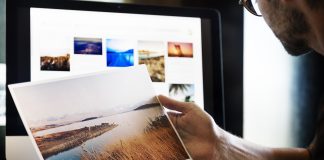 Aplikasi Percuma Untuk Edit Gambar dan Foto Person reviewing a landscape photo print, comparing it to images on a computer screen. Free photo editing app.